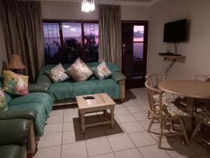 a living room with a green couch and a table at 110 Bay View in Brenton-on-Sea