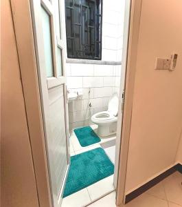 a bathroom with a toilet and green rugs at Warm Haven in Dar es Salaam +18 photos