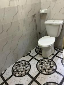 a bathroom with a white toilet and black and white tiles at Al appartement in Cotonou +4 photos