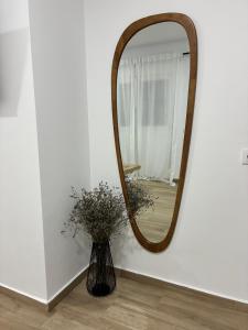 a mirror on a wall next to a vase with flowers at Nuestro lugar feliz Apartamento Barbate - Patio ducha exterior in Barbate +11 photos