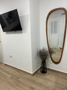 a mirror and a vase with flowers in a room at Nuestro lugar feliz Apartamento Barbate - Patio ducha exterior in Barbate