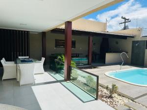 eine Außenterrasse mit einem Pool und einem Haus in der Unterkunft Casa luxo beira mar 5 qtos e piscina in Tamandaré + 16 Fotos
