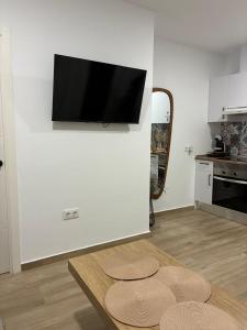 a living room with a table and a tv on a wall at Nuestro lugar feliz Apartamento Barbate - Patio ducha exterior in Barbate
