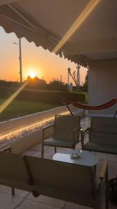 a patio with chairs and a table and the sunset at Beach house in the heart of Athens Riviera in Athens