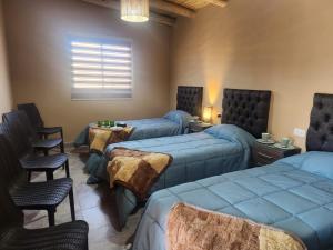 a room with four beds and chairs and a window at Parador Diaguita in El Peñón
