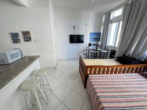 a bedroom with a bed and a kitchen with a tv at Conforto perto do Mar em São Vicente! in São Vicente