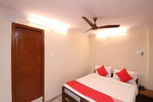 a bedroom with a bed with red pillows and a ceiling fan at Hotel O Midtown in Bhopal