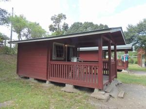 a small red house with a porch on the grass at Eleven Auto Camp Park - Vacation STAY 44746v in Kururi