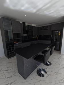a kitchen with a black counter and some chairs at Finca Las palmas Guatape in Guatapé