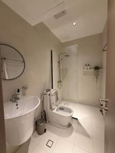 a white bathroom with a toilet and a sink at Onyx F62-2BHK modern classy furnished home with balcony in Muscat +19 photos