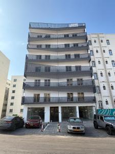 a large building with cars parked in a parking lot at Onyx F62-2BHK modern classy furnished home with balcony in Muscat