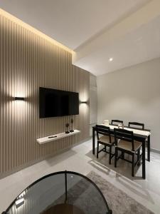 a living room with a table and a television on a wall at Onyx F62-2BHK modern classy furnished home with balcony in Muscat