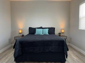 a bedroom with a bed with blue pillows and two lamps at Cozy Home in Visalia