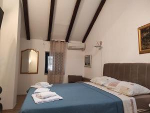 a bedroom with a blue bed with towels on it at Apartments RGETO in Ston
