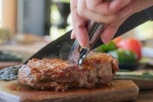 a person cutting a piece of meat with a fork and knife at THE W Relax Garden Resort - Vacation STAY 09071v in Yoshioka