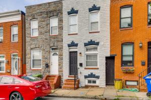 ボルチモアにある2 Blocks to Patterson Park Urban Stay Near Eatsのレンガ造りの建物の前に停車する赤い車