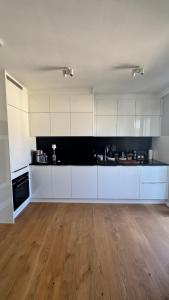 an empty kitchen with white cabinets and a wooden floor at Exklusive 60qm Designerwohnung im Herzen von München - 1 min zur Maximilianstraße in Munich +7 photos