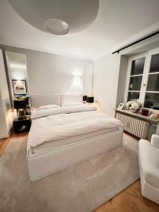 a white bedroom with a large bed and a couch at Exklusive 60qm Designerwohnung im Herzen von München - 1 min zur Maximilianstraße in Munich