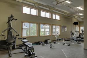 a gym with several treadmills and machines in a room with windows at Alpine Vista - Family Fun Pool & Hot Tub in Canmore