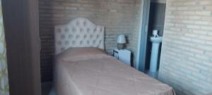 a white bed in a room with a brick wall at Villa Fernandito in Fernando de la Mora