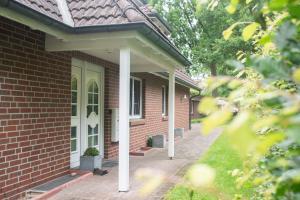a brick house with a white door and a porch at Schnuckenstube Souterrain im Grünen in Schneverdingen