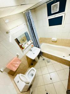 シャルジャにあるOdunmartins apartmentのトイレ、洗面台、浴槽を備えたバスルーム