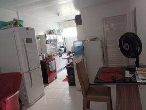 a kitchen with white appliances and a table and chairs at Hospedagem Nininha in Ananindeua +1 photo