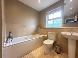 a bathroom with a tub and a toilet and a sink at Spacious 4 Bed Home near Elizabeth Line, perfect for Contractors, Families & Groups in Romford +15 photos