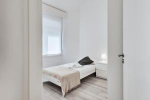 a white bedroom with a bed and a window at San vicente in A Coruña