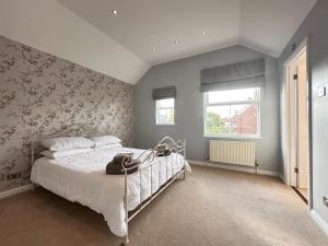 a bedroom with a bed and a wall with floral wallpaper at Spacious 4 Bed Home near Elizabeth Line, great for Contractors, Families, Groups & Insurance stays in Romford