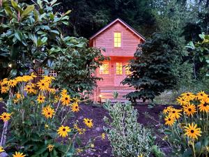a red house in the middle of a garden with flowers at Creekside Bunkies in Roberts Creek
