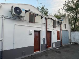a white building with red doors and a fan at MINI HOUSE in Montescaglioso