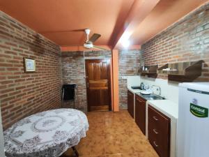 a small kitchen with a brick wall and a table at Departamento 1er Piso-Costa del Potiy in Encarnación