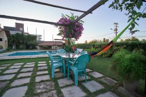 a table and chairs with a hammock in a yard at Casa com Piscina, Churrasqueira e WiFi Cumbuco in Cumbuco