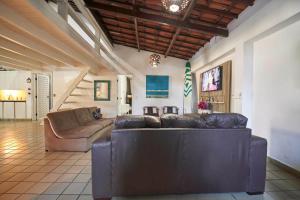 a living room with a leather couch and stairs at Casa com Piscina, Churrasqueira e WiFi Cumbuco in Cumbuco