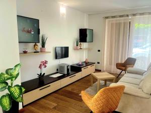 Una sala de estar con un televisor, un sofá y una silla. en Dreamy garda house, en Nago
