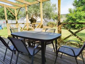 einen schwarzen Tisch und Stühle auf einer Holzterrasse in der Unterkunft Ker EL-RAPHA in Saint-Avé