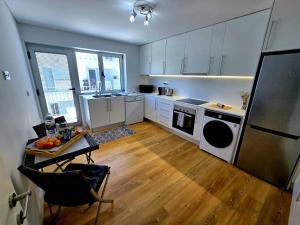 a kitchen with white cabinets and a table and a refrigerator at Lagoa Nest in Lagoa