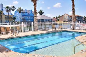 a swimming pool with chairs and a fence with palm trees at Compass Condominiums A3 in Corpus Christi