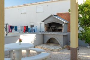 a patio with a brick fireplace and a table and chairs at Apartment Draga in Vir