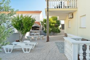 un patio avec bancs blancs et un bâtiment dans l'établissement Apartment Draga, à Vir
