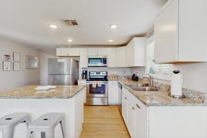 een keuken met witte kasten en roestvrijstalen apparaten bij Flip Flop Cottage in Rockport