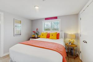 een slaapkamer met een wit bed met gele en oranje kussens bij Flip Flop Cottage in Rockport
