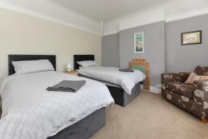 a bedroom with two beds and a couch at Dolwar in Abersoch