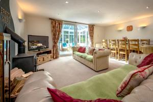 a living room with couches and a television and a living room with a table at Bragdy Wern in Llanbedrog