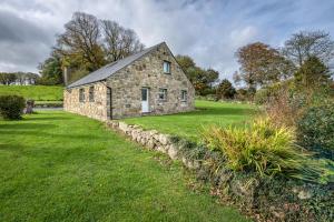 an old stone house in a field with grass at Bragdy Wern in Llanbedrog