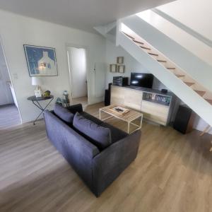 een woonkamer met een bank en een trap bij Détente à la mer Blanche in Fouesnant