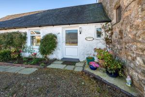 a white cottage with a door and some plants at The Cottage in Llanbedrog