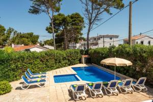 a swimming pool with lounge chairs and an umbrella at Villa Gatzara by Villa Plus in Cala Blanca