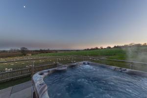 a hot tub on a fence next to a field at Churchlands Barn in Stone